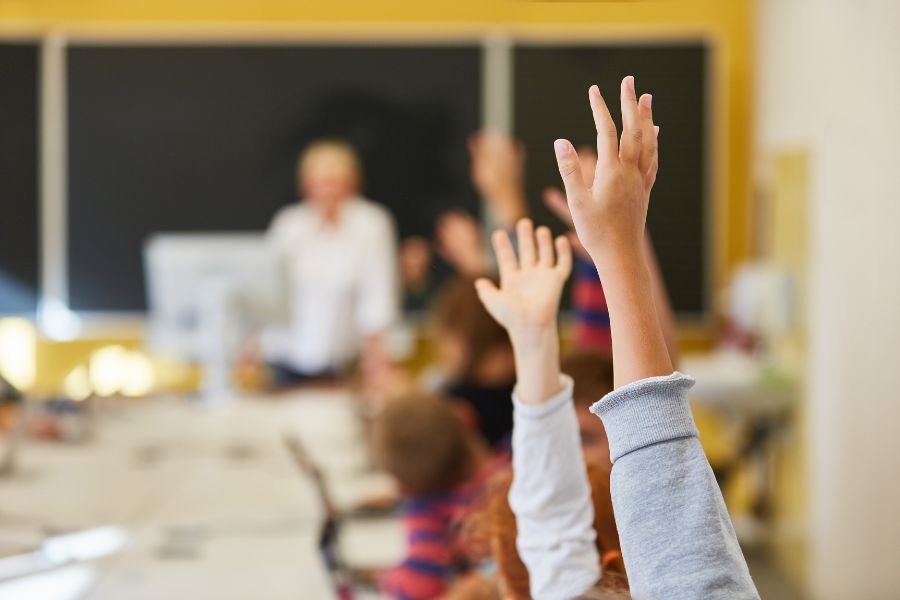 manos alzadas de unos alumnos en clase