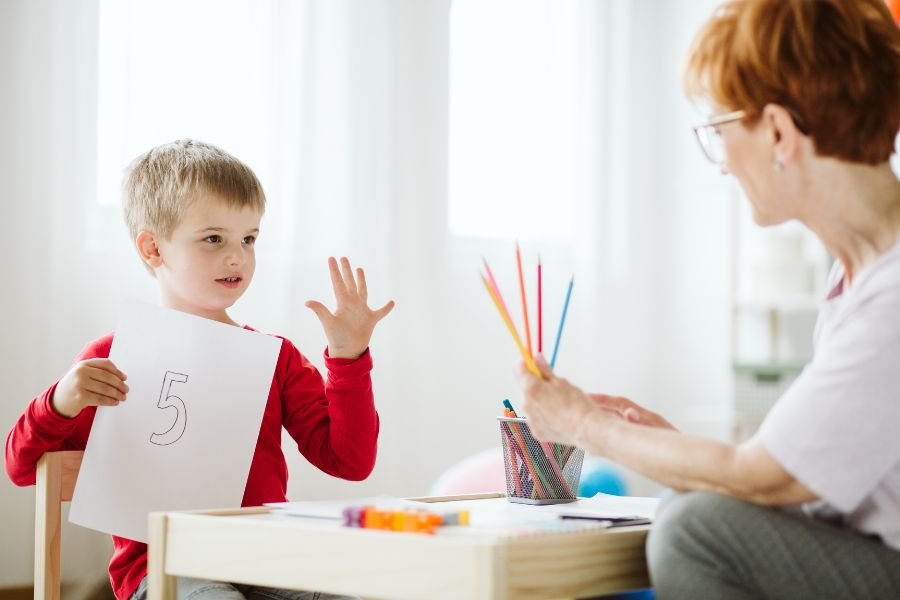 profesora enseña a un niño el número cinco